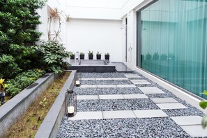 A modern outdoor pathway with a checkered tile pattern, surrounded by greenery and potted plants. - All-Ur Boutique Motel - Xin-Jhung Branch (New Taipei City)