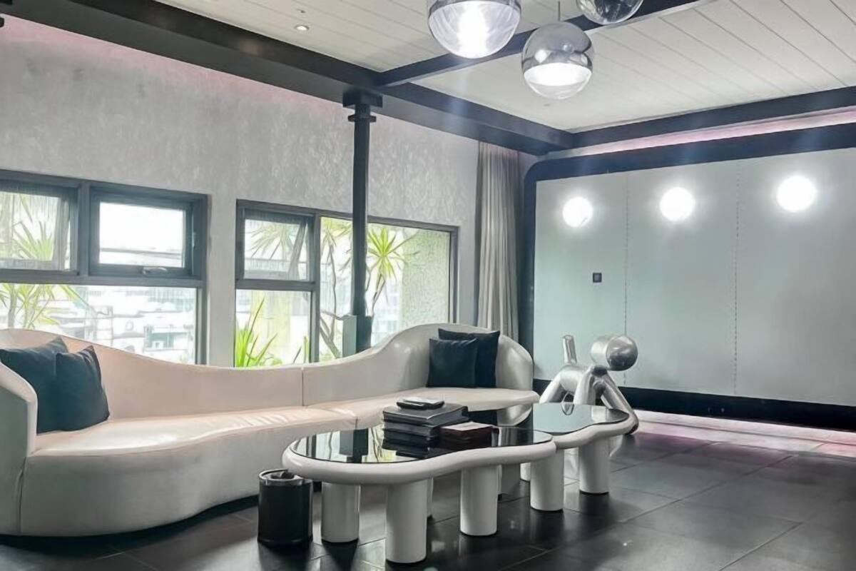 A modern living room with a white sofa, a glass coffee table, and a unique sculpture.