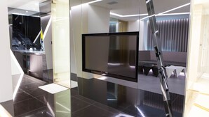 A modern hotel room with a large flat-screen TV mounted on a wall, a glass partition, and a sleek, minimalist design. - All-Ur Boutique Motel - Xin-Jhung Branch (New Taipei City)