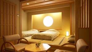 Una habitación tradicional japonesa con dos camas individuales, una mesita con un jarrón de flores y muebles de madera.