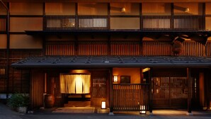 Un edificio japonés tradicional con fachada de madera, techo de tejas y un farolillo al frente.