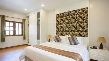 A neatly arranged bedroom with a large bed, a nightstand, a lamp, and a window with curtains.