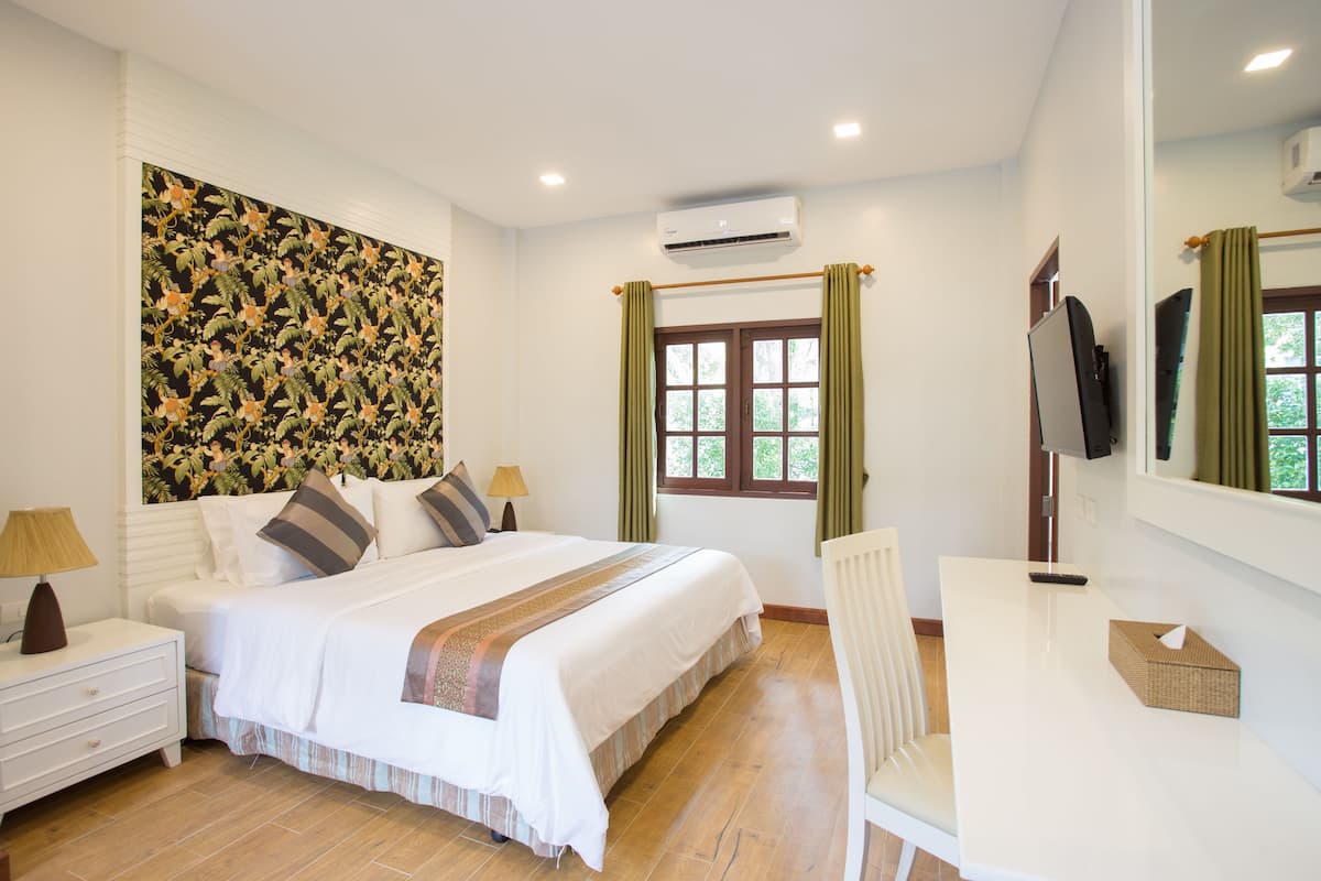 A bedroom with a bed, bedside tables, a desk, and a TV.