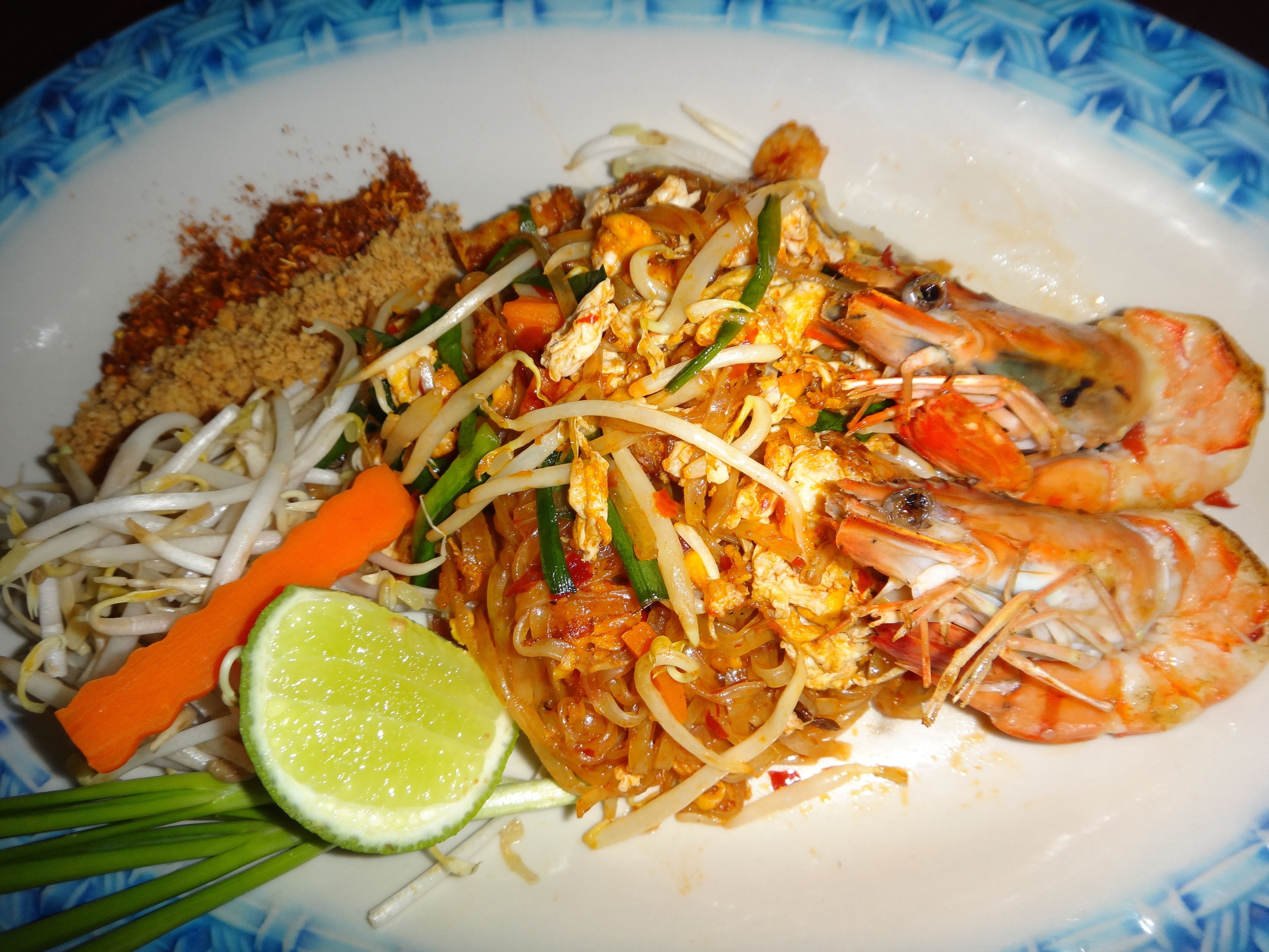 Un plato de Pad Thai con camarones, brotes de soja y lima.