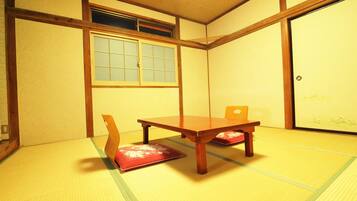 A traditional Japanese room with tatami flooring, a low wooden table, and a sliding door.