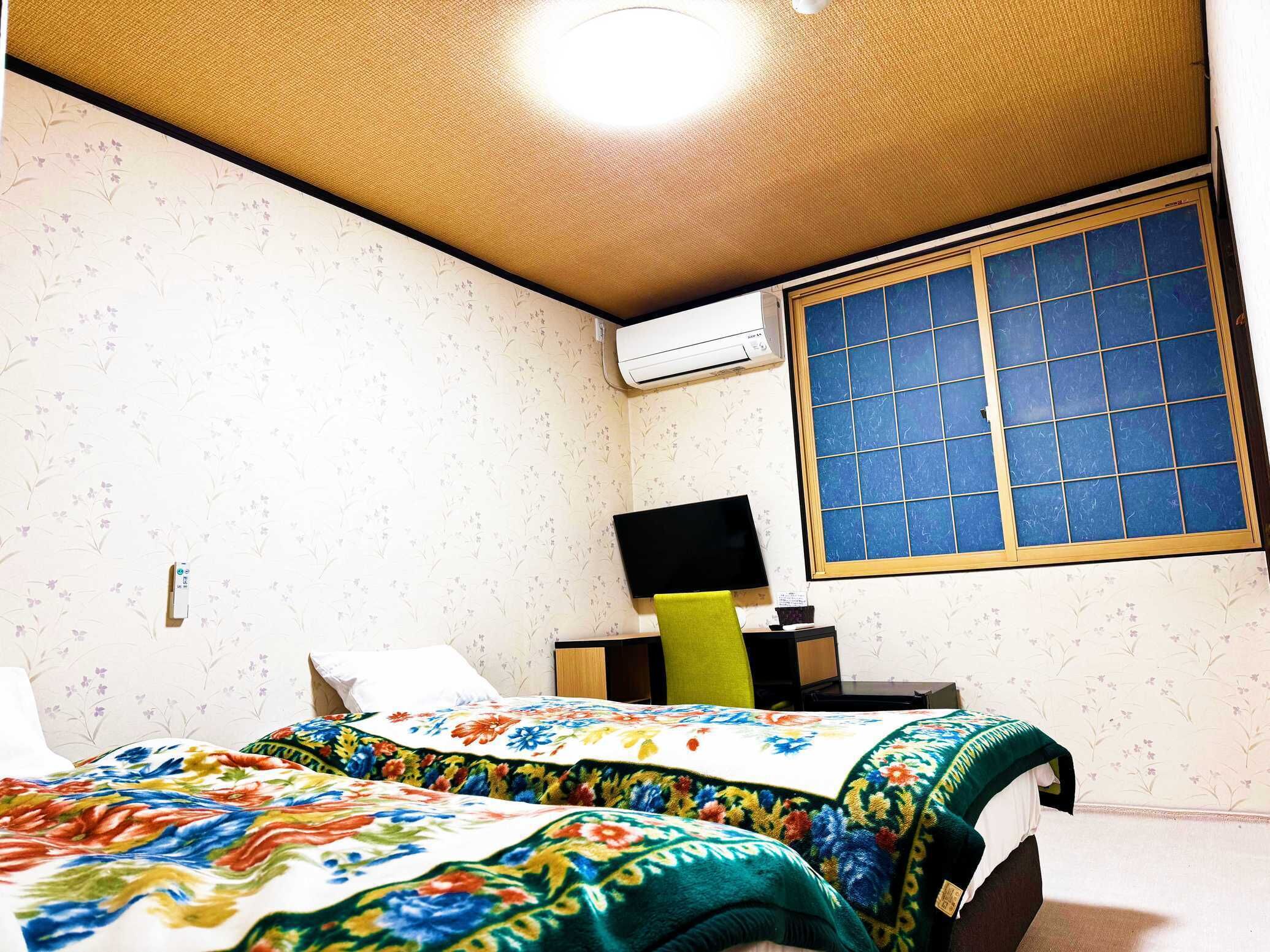 Une chambre à coucher comprenant un lit, un bureau, une chaise et une fenêtre avec du verre teinté en bleu.