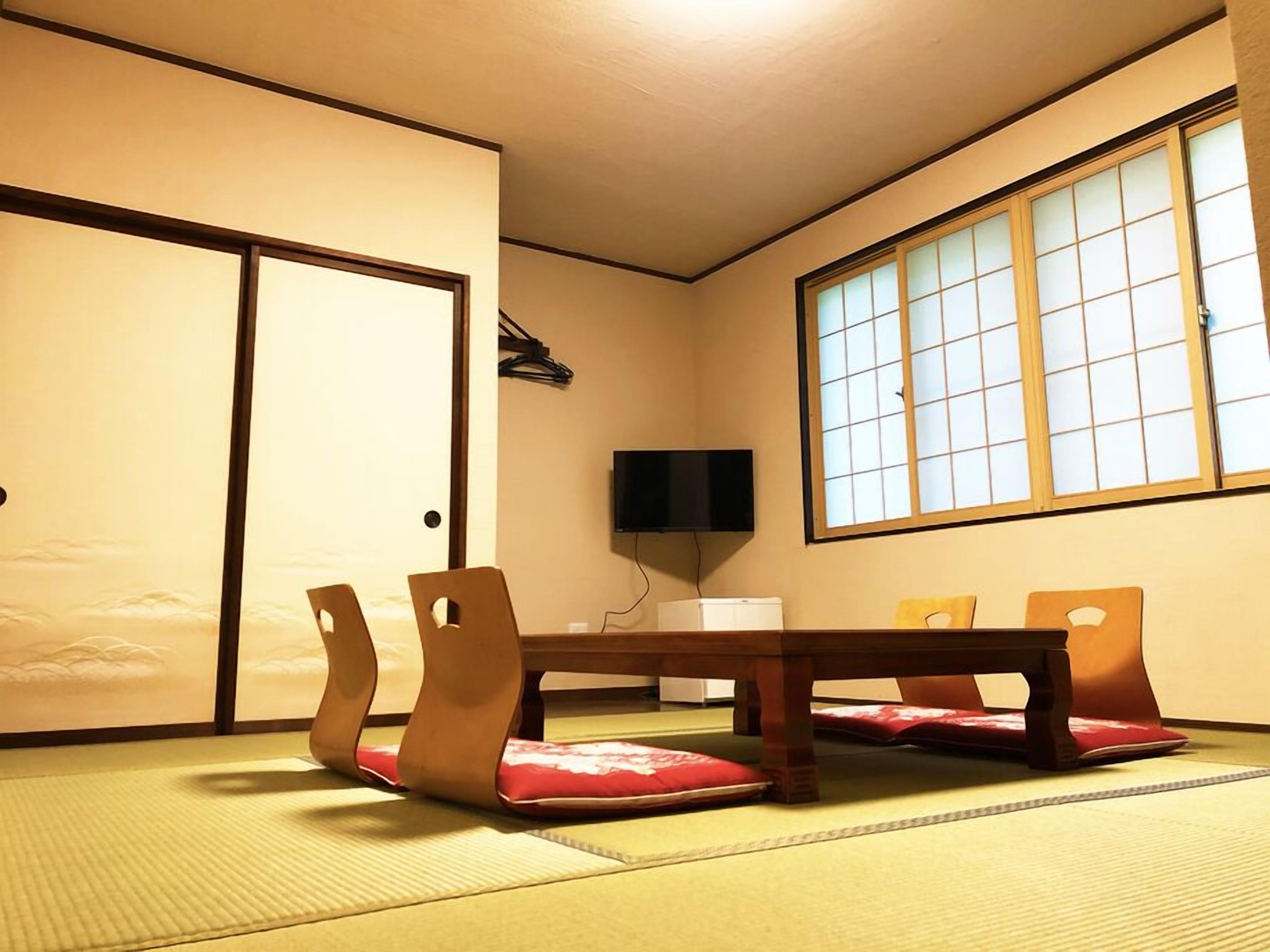 Une pièce de style japonais traditionnel, avec un sol recouvert de tatamis, une table basse et quatre chaises.