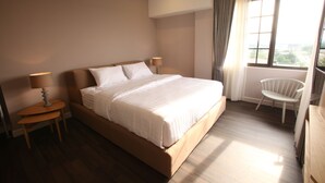 Un dormitorio con una cama grande, dos mesitas de noche, una silla y una ventana con cortinas.