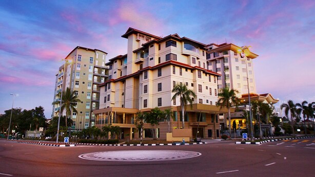 Un hotel de varios pisos con un patio central, palmeras y una glorieta.