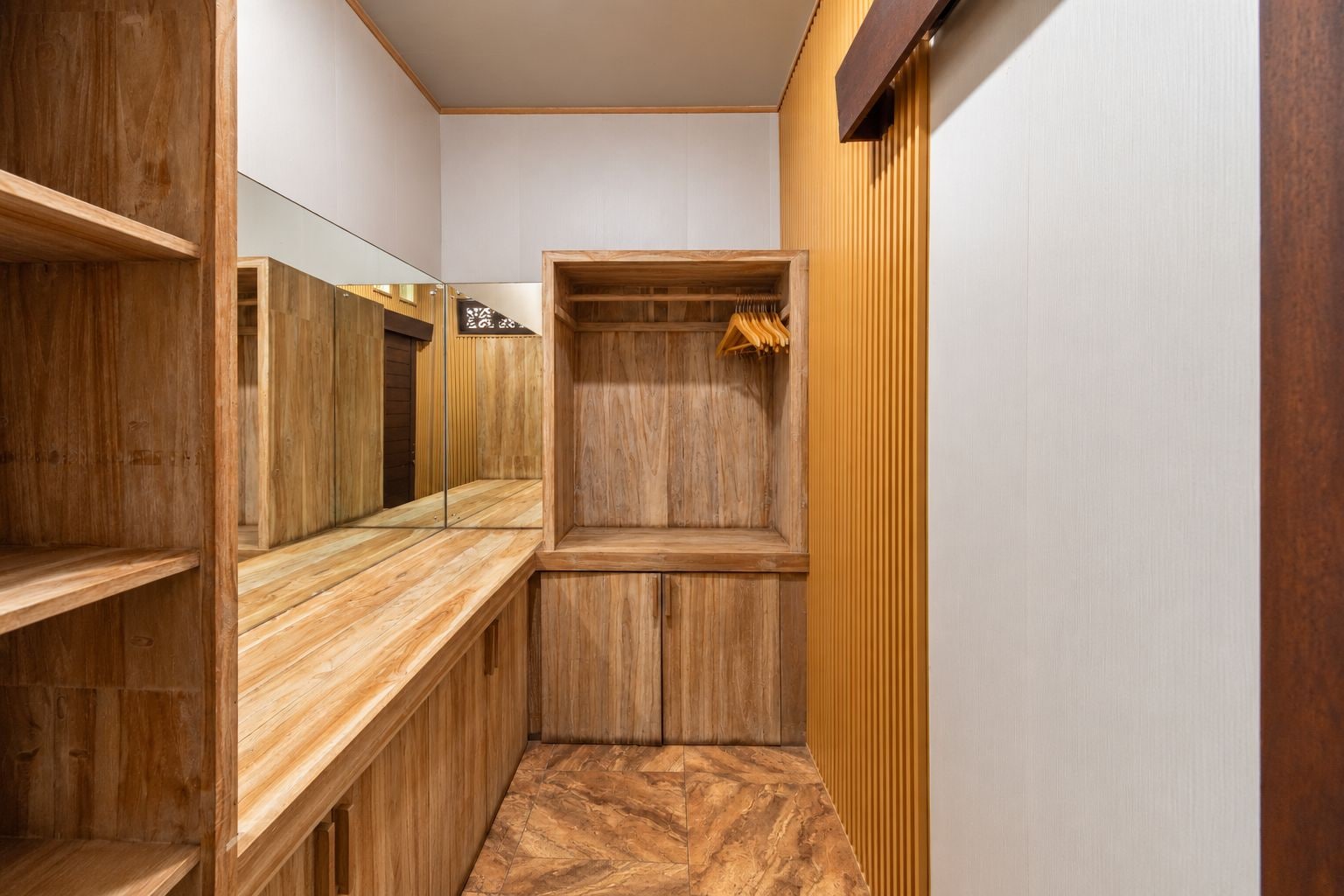 Un couloir étroit aux murs en bois et doté d’une coiffeuse avec un grand miroir.