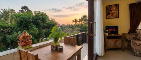 A balcony with a wooden table, a potted plant, and a decorative item.