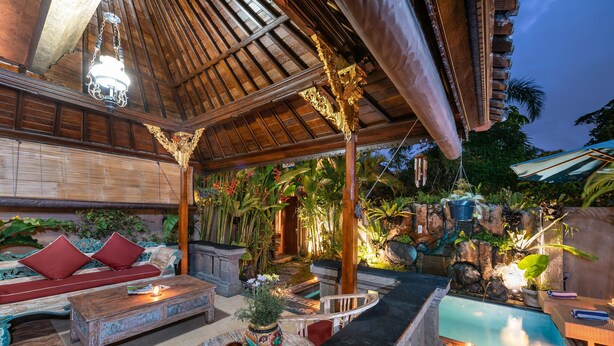 Un área de piscina interior con un banco de madera y una mesita con un florero.