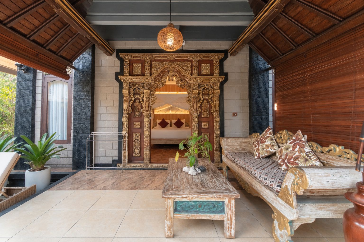 A room with a traditional wooden archway, a sofa with patterned cushions, a wooden coffee table, and a hanging light fixture.