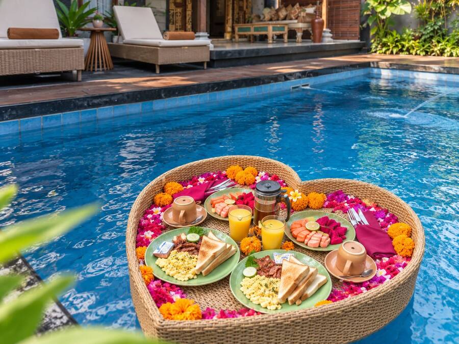 Un plateau flottant en forme de cœur, sur lequel sont disposés des aliments pour le petit-déjeuner et des boissons, et qui est placé dans une piscine.