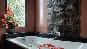 A bathroom with a bathtub, a shower, and a window with a flower arrangement. - Ashanti Villa Ubud (Ubud)