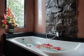 A bathroom with a bathtub, a shower, and a window with a flower arrangement. - Ashanti Villa Ubud (Ubud)