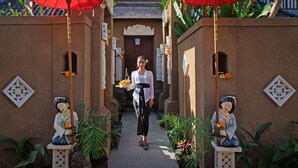 A pathway flanked by statues and red umbrellas, leading to a door with a decorative ceiling. - Ashanti Villa Ubud (Ubud)