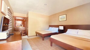 A hotel room with two beds, a desk, a chair, a television, and a bathroom visible through an open door. - Anaya Beach Resort (Bantayan)