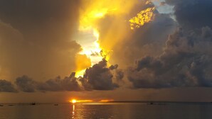 A sunset over a calm sea with boats and a distant shoreline. - Anaya Beach Resort (Bantayan)