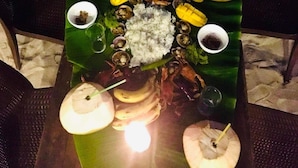 A table set with a variety of dishes, including rice, seafood, and vegetables, arranged on a banana leaf. - Anaya Beach Resort (Bantayan)
