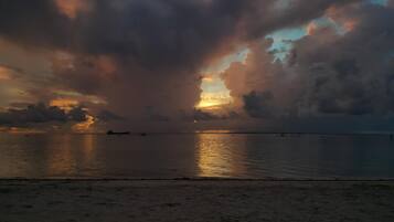 A beach with calm waters and a sunset.