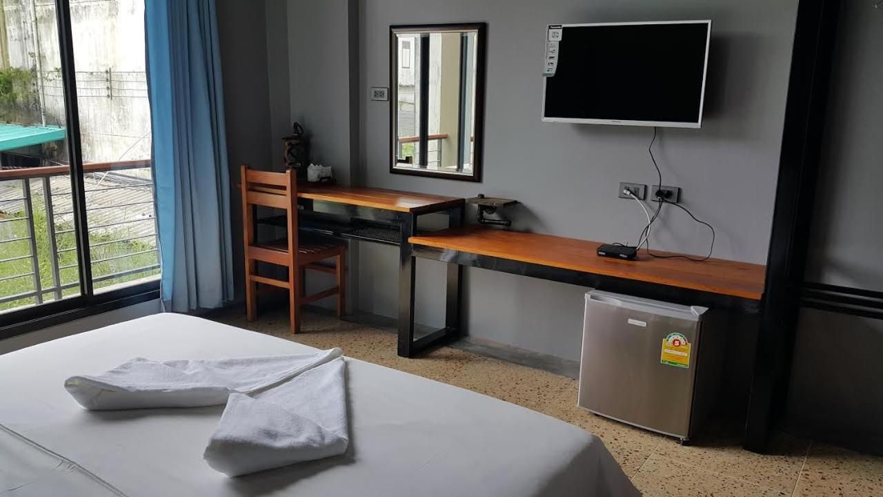 A hotel room with a bed, a desk, a chair, a television, and a refrigerator.