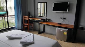 A hotel room with a bed, a desk, a chair, a television, and a refrigerator.