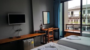 Une chambre d’hôtel équipée d’un lit, d’un bureau, d’une chaise, d’une télévision et d’une fenêtre donnant sur des immeubles.
