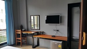 Une petite pièce comprenant un bureau, une chaise et un téléviseur fixé au mur.