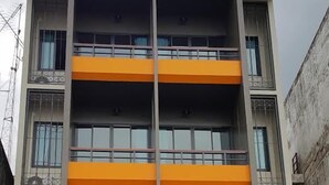 Un immeuble à plusieurs étages doté d’un atrium central, de balcons à chaque étage et d’une entrée au niveau du sol avec une porte en verre.