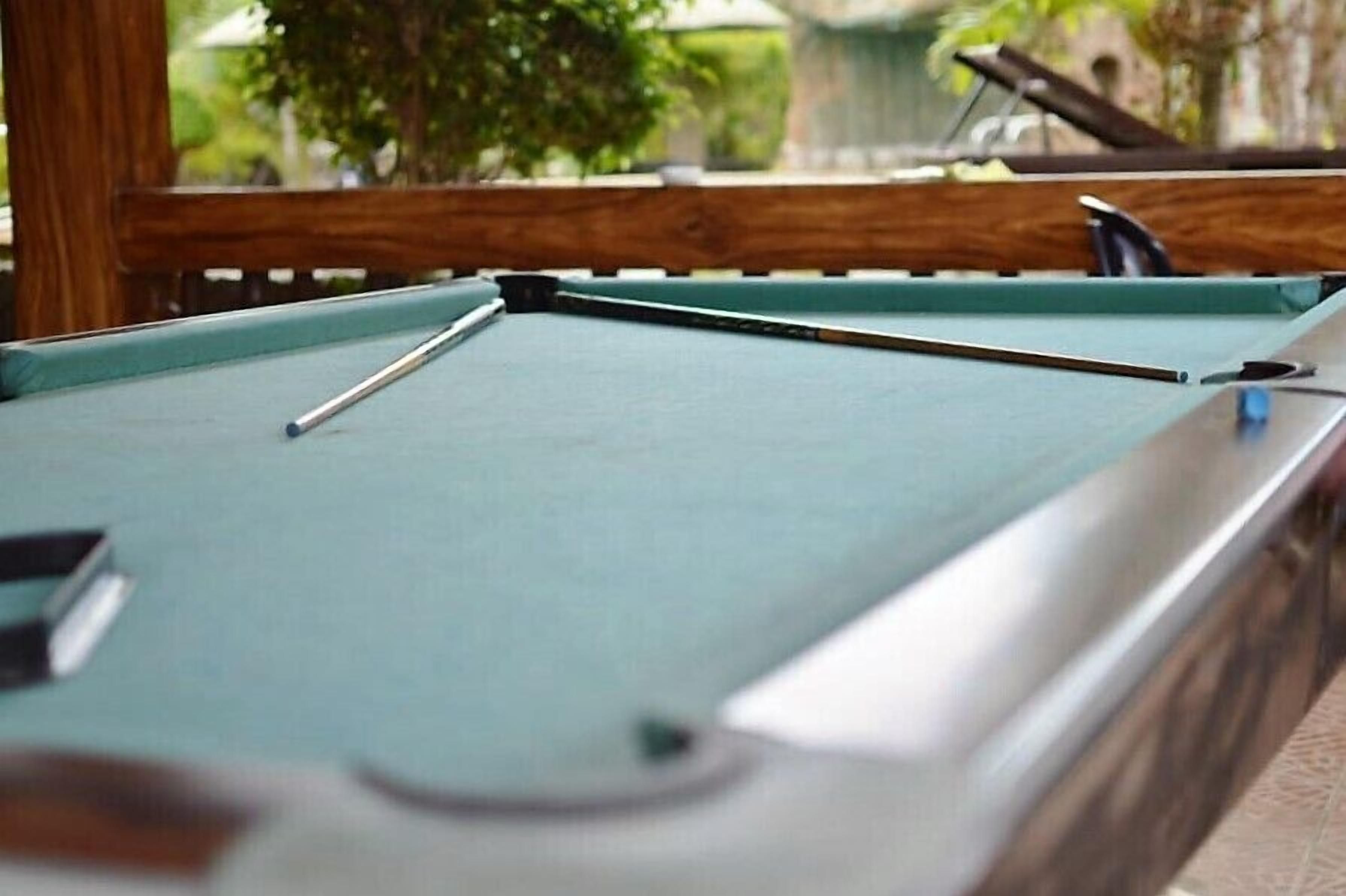 Una mesa de billar con estructura de madera y superficie de fieltro verde.