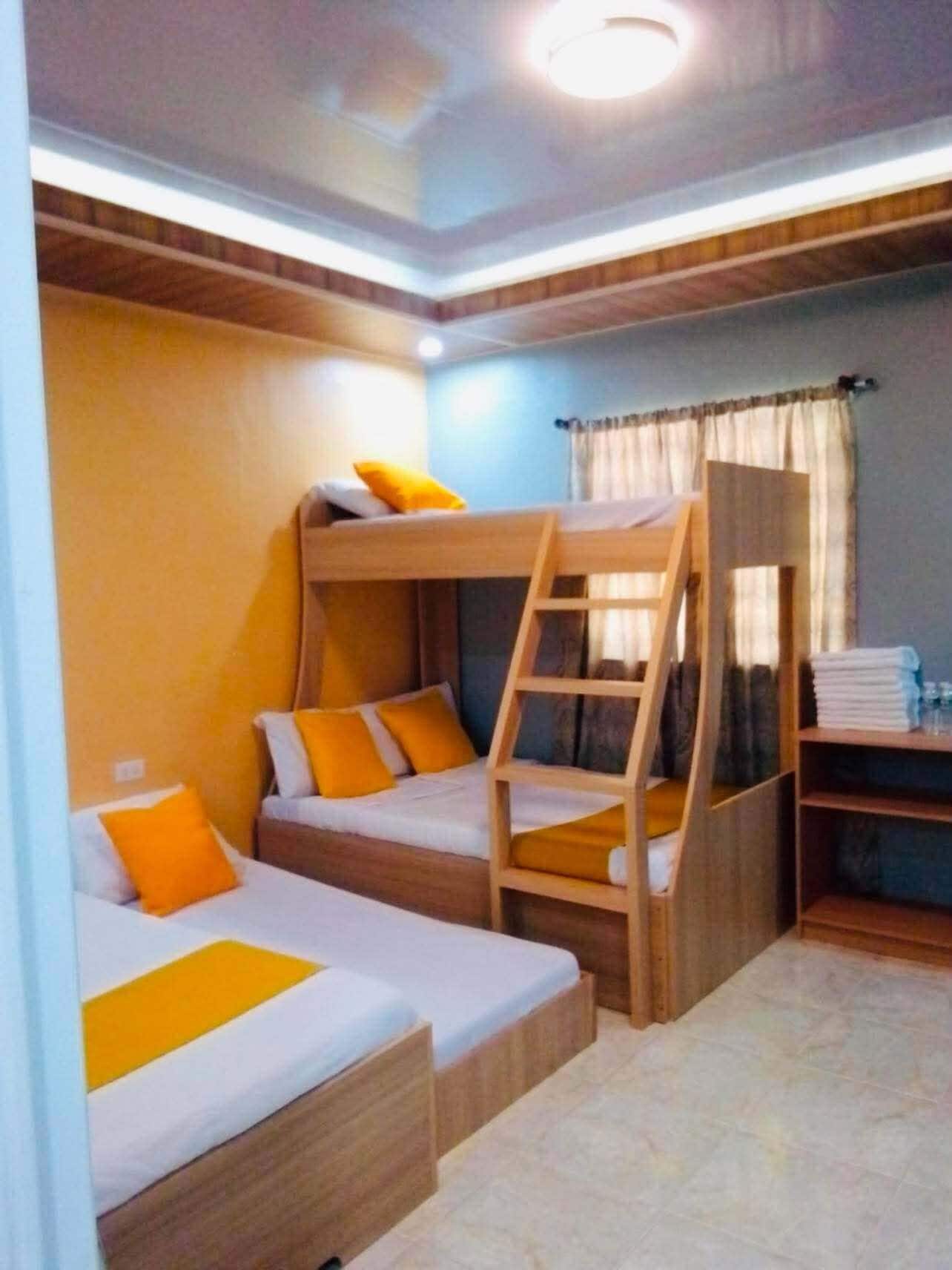 A room with bunk beds, a ladder, and a small desk with a chair.