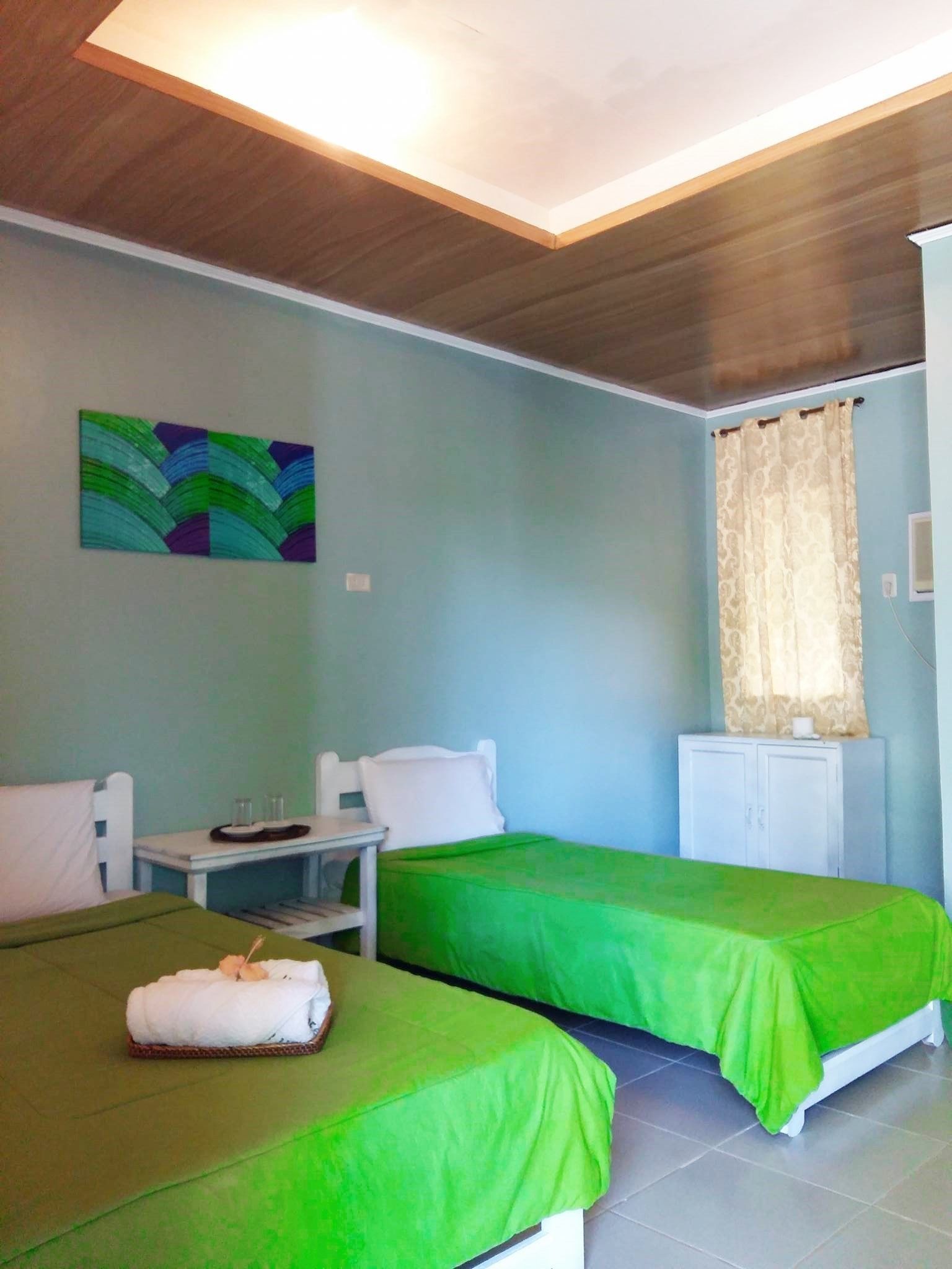 A room with two beds, a desk, a chair, a cabinet, and a painting on the wall.