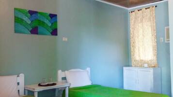 A room with two beds, a desk, a chair, a cabinet, and a painting on the wall.