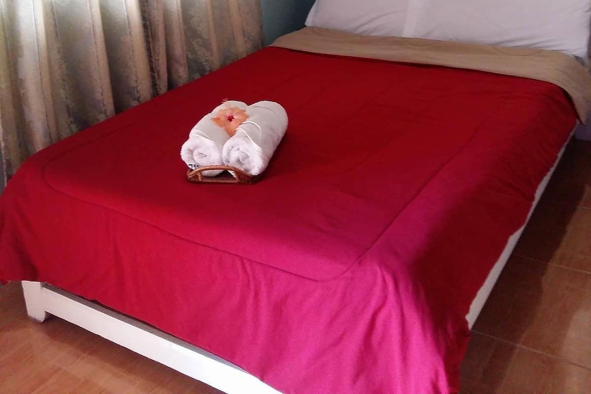 Une chambre d’hôtel avec un lit, une couvre-lit rouge et un oreiller blanc.