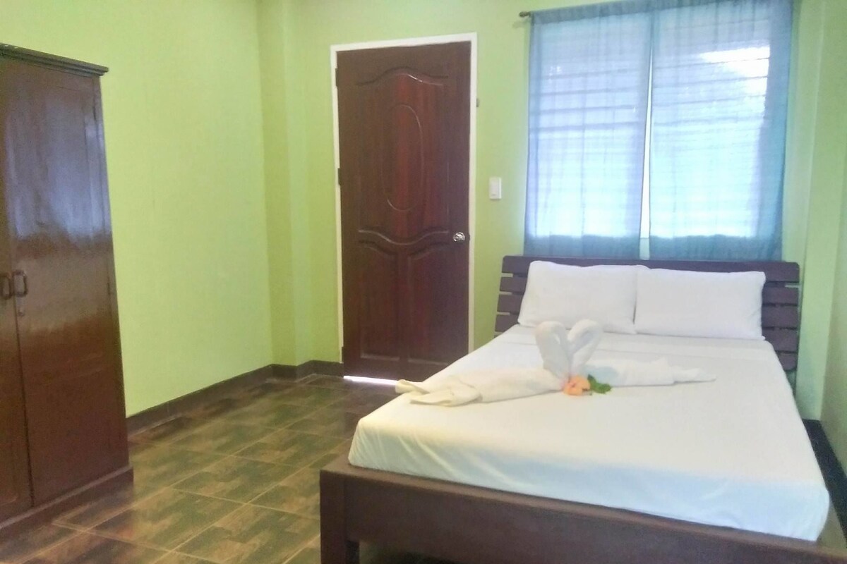 A bedroom with a bed, a wooden wardrobe, and a door.