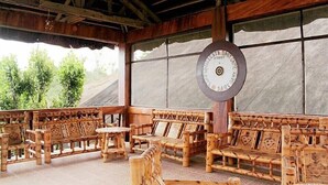 Un espacio de estar al aire libre cubierto con muebles de madera y un reloj grande.