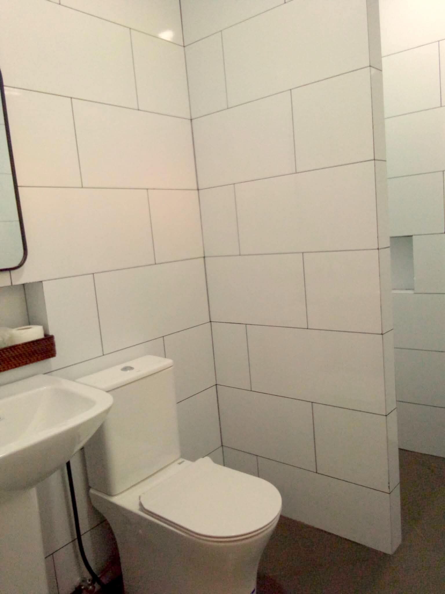 Ein Badezimmer mit einer weißen Toilette, einem weißen Waschbecken und einem Spiegel an der Wand.