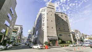 A hotel with a prominent 'HOTEL' sign on the facade, multiple floors, and a parking area with cars. - H Hotel Ulsan (Ulsan)