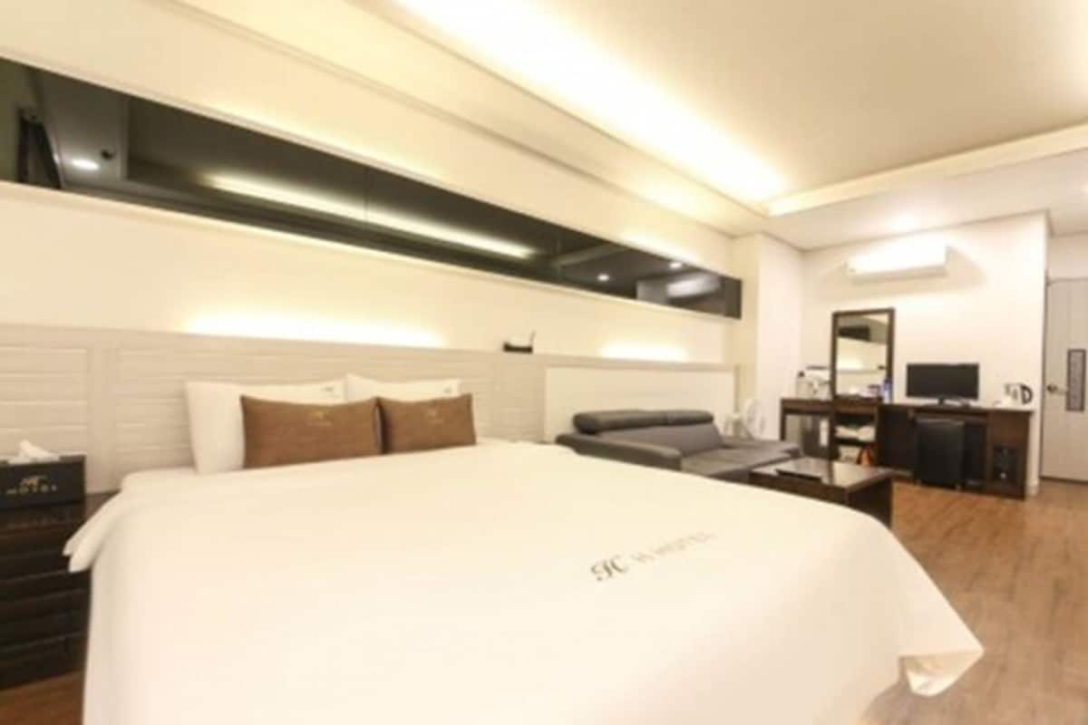 Una habitación de hotel moderna con una cama grande, un escritorio y una televisión.
