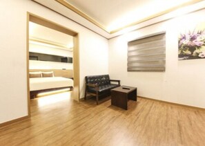 A hotel room with a bed, a sofa, a small table, and a window with blinds. - H Hotel Ulsan (Ulsan)