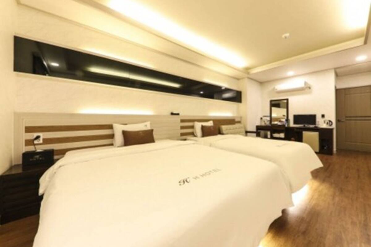 Una habitación de hotel con dos camas, un escritorio, una silla y un armario.