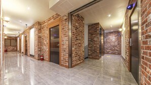 A hallway with brick walls, elevators, and a polished floor. - H Hotel Ulsan (Ulsan)