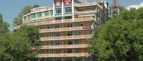 A multi-story hotel with balconies, a prominent sign reading "MOVE-N-PICK HOTEL," and a communication tower in the background.