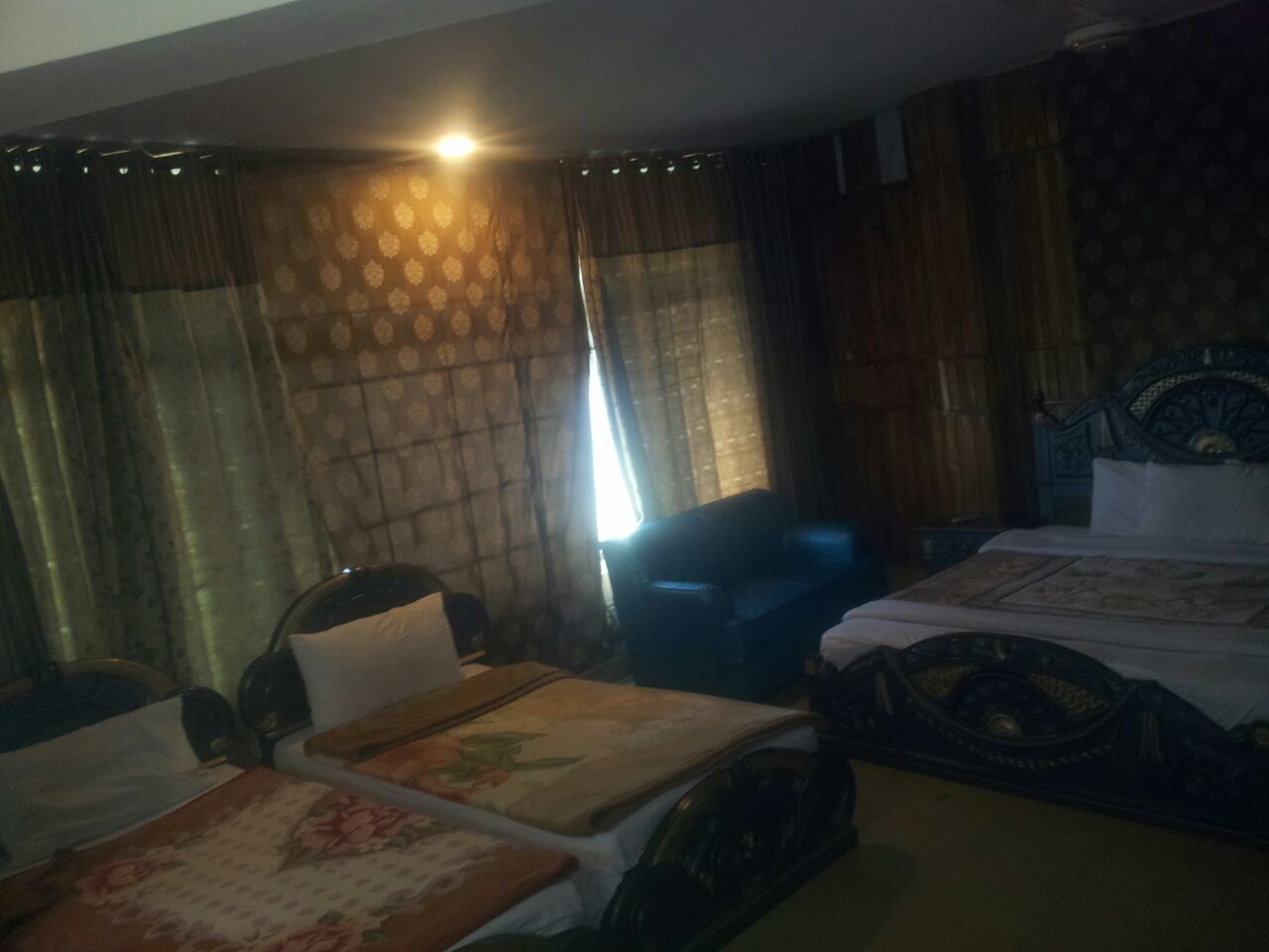 Une chambre d’hôtel avec deux lits, une chaise et une fenêtre avec des rideaux.
