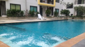 A swimming pool with clear blue water, surrounded by a tiled deck. - Ratchaporn Place (Kathu)