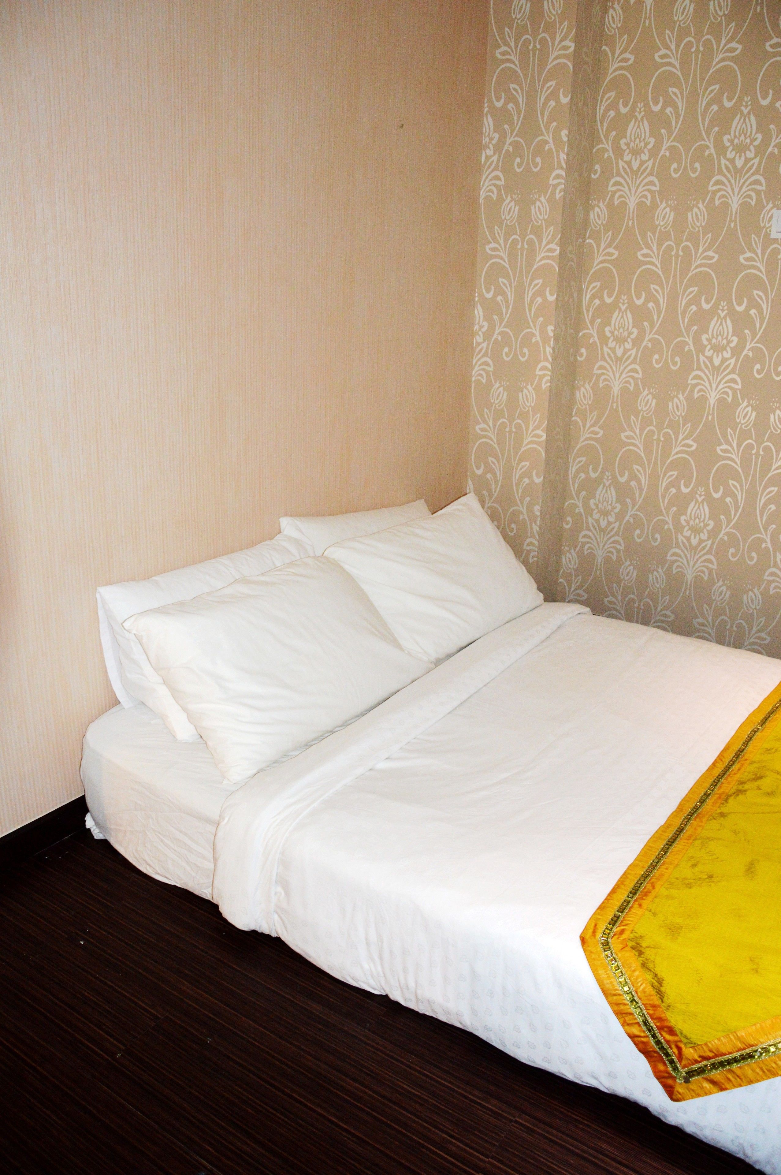 A neatly made bed with white bedding and a yellow accent on the footboard.