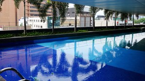 Una piscina con agua azul cristalina, rodeada de vegetación y edificios modernos.