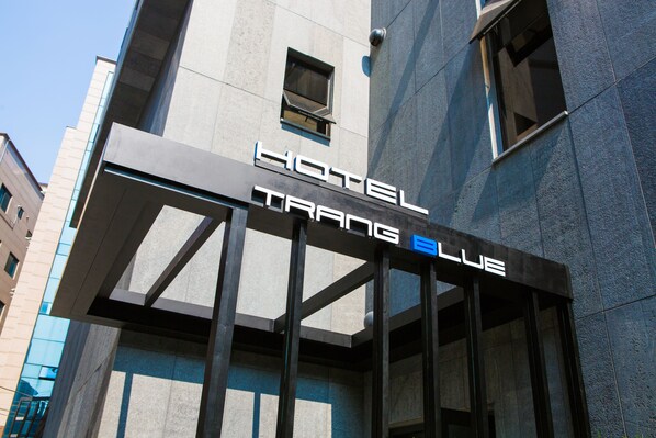 A hotel entrance with a modern design, featuring a prominent sign that reads "HOTEL TRANG BLUE."