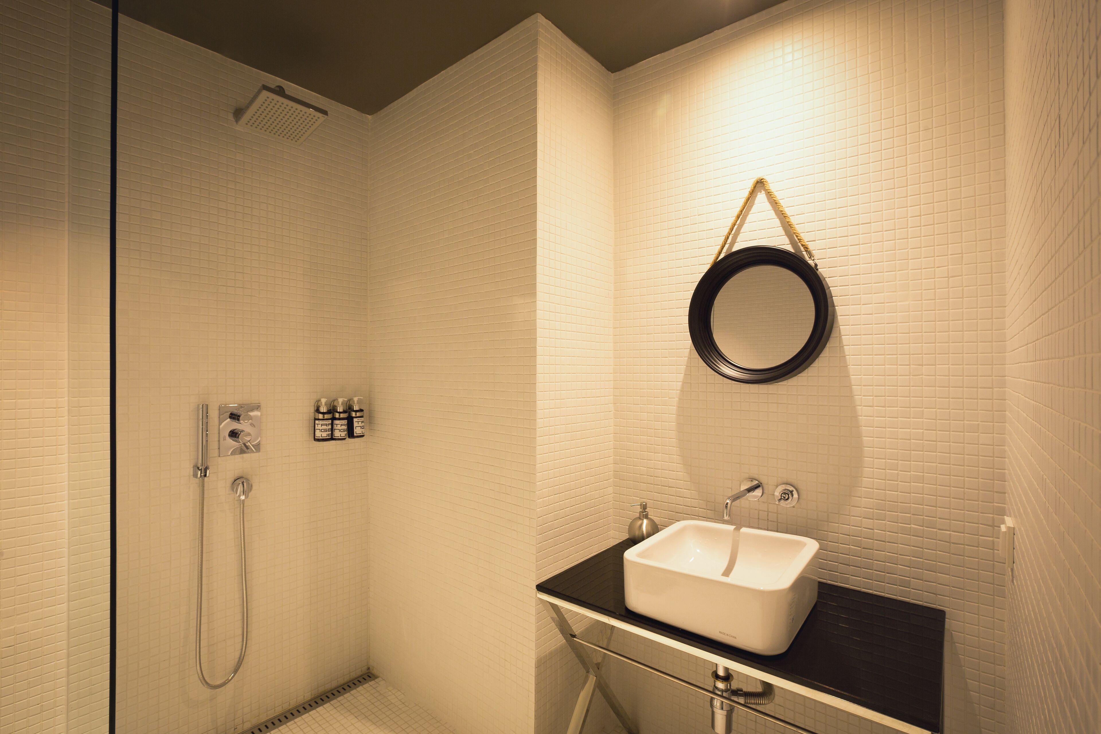 A bathroom with a shower, a sink, and a mirror.